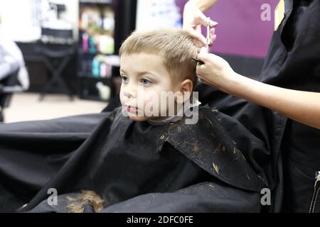 Ragazzo che ottiene il taglio dei capelli nel salone del parrucchiere Foto Stock