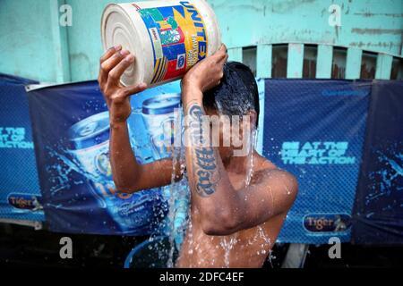 Myanmar (Birmania), un ragazzo versa acqua su se stesso in una strada a Rangoon Foto Stock