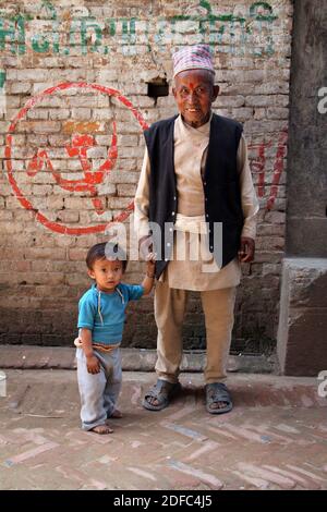 Nepal, ritratto del nonno nepalese Newar con nipote con simbolo comunista Foto Stock