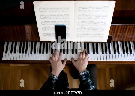 Insegnante che suona il pianoforte durante la sua lezione online Foto Stock