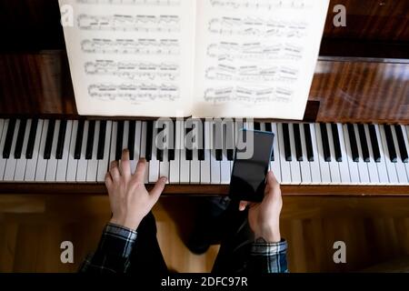 Insegnante che suona il pianoforte durante la sua lezione online Foto Stock