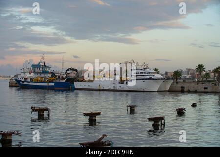 Tripoli, Libia - 25 novembre 2020: Il porto di Tripoli durante il tramonto in una normale giornata lavorativa. Foto Stock