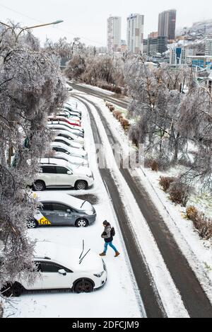 Vista della città e delle strade in cattive condizioni di neve. Auto coperte di ghiaccio, neve e ghiaccioli. Scene gelate invernali. Ciclone della tempesta di ghiaccio. Foto Stock