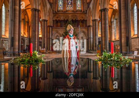 Il chorister Sebastian Kunzer, 13 anni, si trova accanto al fonte battesimale mentre si abitua a indossare gli abiti del vescovo mentre prova il suo ruolo di chorister Bishop alla Cattedrale di Salisbury nel Wiltshire. Durante l'evento annuale, che si svolge intorno al giorno di San Nicola, un coro è scelto per agire come vescovo per un breve periodo in avvento in una consuetudine medievale di inversione di ruolo, in cui maestri e servitori scambiano posti per un incantesimo. Foto Stock