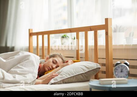 Giovane donna che dorme nel suo letto di mattina presto dentro la camera da letto a casa Foto Stock