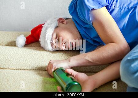 Un uomo a Santa Hat che dorme sul divano con Una birra Foto Stock