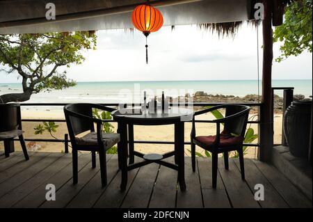 Tavolo con due sedie a sdraio in spiaggia vuota ristorante abbandonati dai clienti a causa di forte pioggia. Foto Stock