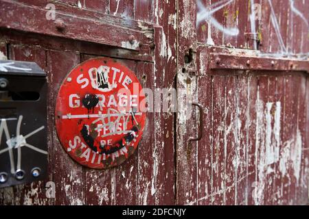 Vintage, weatherd cancello in legno con pareti scrostate. Cartello in francese 'uscita di garage, parcheggio vietato". Vecchia casella postale in primo piano. Parigi, Francia. Foto Stock