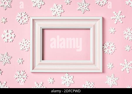 Composizione invernale. Cornice fotografica e fiocchi di neve su sfondo rosa pastello. Concetto di vacanza invernale. Vista dall'alto, disposizione piatta, spazio per la copia. Foto Stock