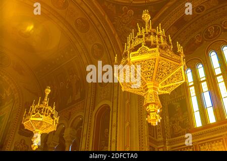 Vista dal basso su lampadari dorati appesi sul soffitto, all'interno della vecchia cattedrale ortodossa di Timisoara, Romania. Foto Stock