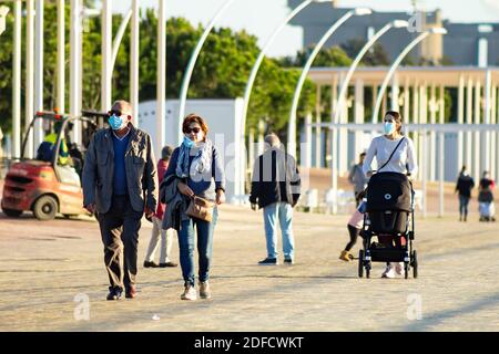 Huelva, Spagna - 3 dicembre 2020: Coppia a piedi dalla passeggiata Huelva al tramonto, indossare maschere protettive o mediche durante lo stato di allarme e qu Foto Stock