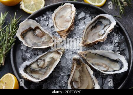 Ostriche fresche aperte su ghiaccio, fondo testurizzato Foto Stock