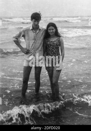 Anni '60 anni '70 mare aperto giovane coppia in bianco e nero divertirsi alla spiaggia toscana di Castinglioncello. Italia. Scansione di graffi e difetti Foto Stock