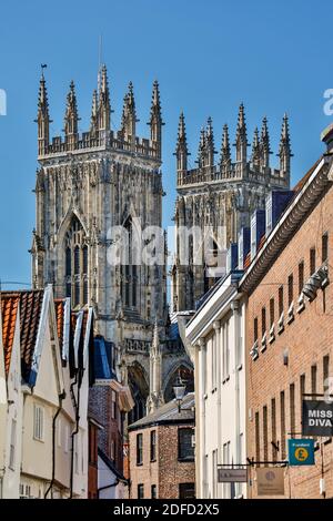 Negozi, insegne e torri di York Minster (la Cattedrale e la Chiesa Metropolitan di San Pietro) nel retro, York, Yorkshire, Inghilterra, Regno Unito Foto Stock