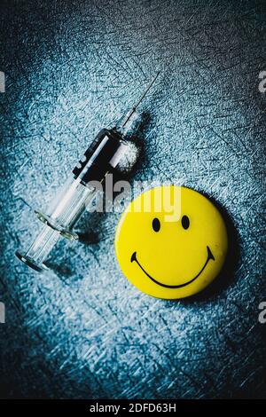 Siringa di vaccinazione e simbolo del viso sorridente. Foto Stock