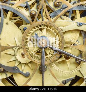 Innerworks di un antico orologio con ruote dentate e ora e la mano del minuto Foto Stock