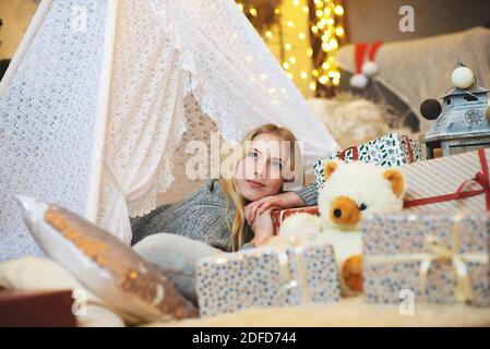 Bella donna donna che si stagliano su giftbox di Natale indossare pullover lavorato a maglia e cappello di santa in soggiorno Foto Stock