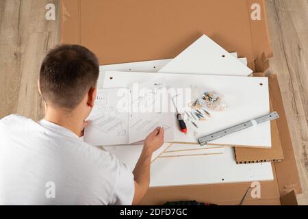 Giovane uomo che monta nuovi mobili a casa Foto Stock