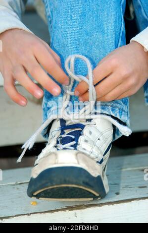 Quattro anni di apprendimento del ragazzo di legare le scarpe Foto Stock