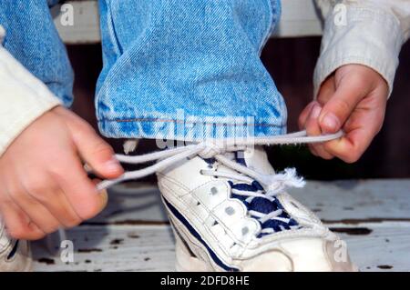 Ragazzo di quattro anni imparando a legare i lacci delle scarpe Foto Stock