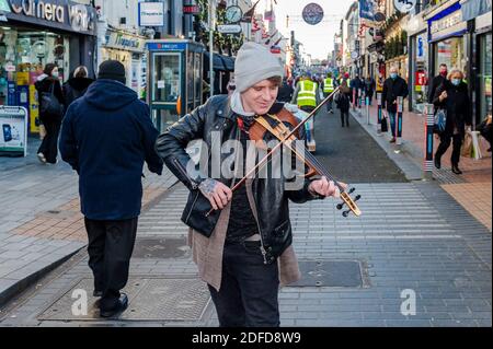 Cork, Irlanda. 4 Dicembre 2020. Ora che le restrizioni COVID-19 di livello 5 sono state attenuate, la città di Cork era occupata oggi con gli acquirenti che fanno il loro shopping di Natale. I ristoranti e i pub che servono cibo hanno aperto le loro porte ai commensali oggi, ma con rigide linee guida di allontanamento sociale in atto. Ryan Parsons di Blackrock stava busking con il suo violino su Oliver Plunkett Street. Ryan ha detto che non ha ridacchiato per un anno a causa delle restrizioni COVID-19. Credit: AG News/Alamy Live News Foto Stock