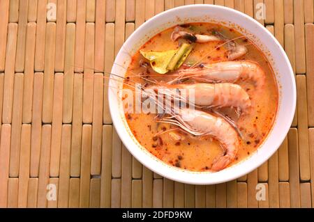 Gamberetti bolliti con erbe in zuppa piccante tailandese o tom yum kung sulla ciotola Foto Stock