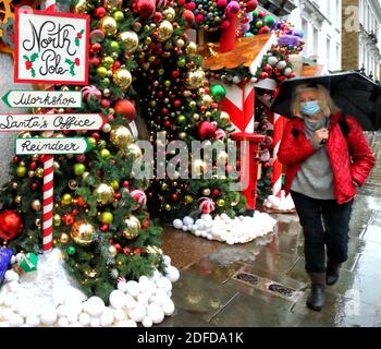 Londra, Regno Unito. 03 dic 2020. Una donna passa accanto al Ivy Chelsea Garden.The Ivy Chelsea Garden si è trasformato in Grotta di Santa per Natale. Il ristorante alla moda lungo la King's Road ha avuto un restyling festivo con l'installazione che include la mailroom di Babbo Natale, le scuderie di renna, l'albero di Natale, le decorazioni e la slitta di Babbo Natale. Credit: SOPA Images Limited/Alamy Live News Foto Stock