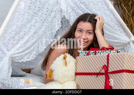 Bruna ragazza adolescente che si trova tra scatole regalo di natale e giocattoli, Natale concetto Foto Stock