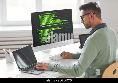 Programmatore maschio che lavora su computer desktop con molti monitor a. azienda di sviluppo software office Foto Stock