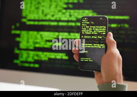 Primo piano dello sviluppatore che scrive il codice di programmazione sul telefono cellulare e. computer Foto Stock