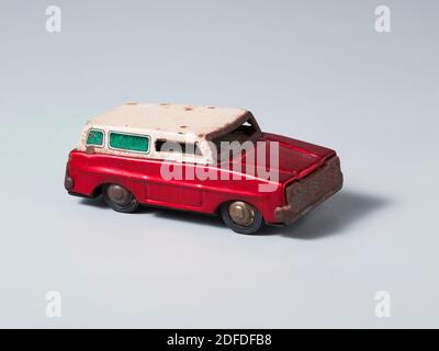 Un furgone vintage giocattolo in lattina in rosso e bianco su uno sfondo grigio Foto Stock