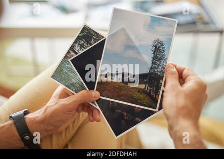 Primo piano di un uomo che tiene foto con splendidi paesaggi nel suo mani Foto Stock