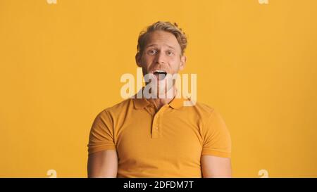 Giovane eccitato uomo bearded guardando stupito isolato su sfondo giallo. WOW emozione Foto Stock