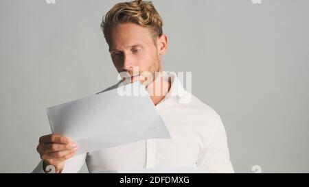 Giovane uomo d'affari concentrato bearded in camicia che lavora con i documenti di affari isolato su sfondo bianco Foto Stock