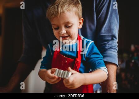 Adorabile ragazzo che prepara biscotti di natale con il viso pieno di farina Foto Stock