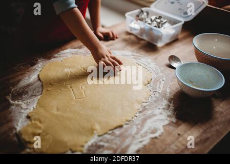 Primo piano di una mano del bambino che fa i biscotti di Natale con una taglierina Foto Stock