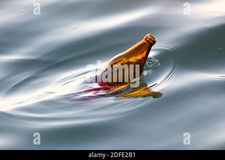 Una bottiglia di vetro marrone che galleggia nell'oceano Foto Stock
