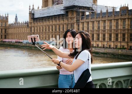 Due giovani donne asiatiche prendono un selfie con il telefono cellulare, Westminster Bridge. Londra, Inghilterra, Regno Unito, Europa Foto Stock