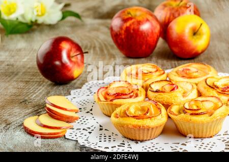 In rose a forma di muffin di mela su sfondo di legno. Torta dolce di mele. Pasticceria fatta in casa di mela rosa. Foto Stock