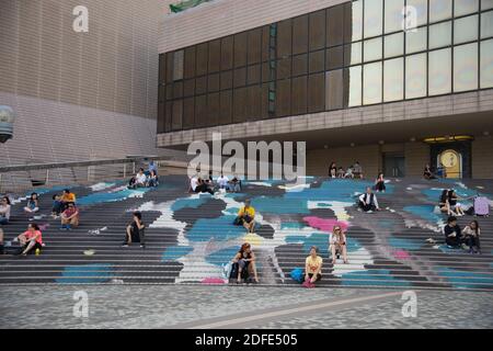 Gli studenti si rilassano sui gradini della biblioteca cittadina, Hong Kong, Cina Foto Stock