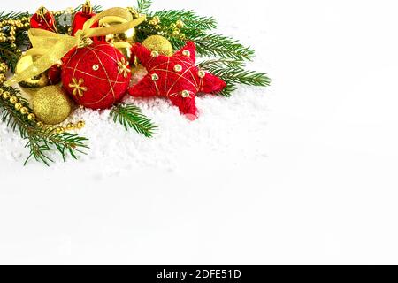 Ornamenti natalizi rossi e dorati nella neve. Decorazione di Natale su sfondo bianco. Spazio di copia. Foto Stock