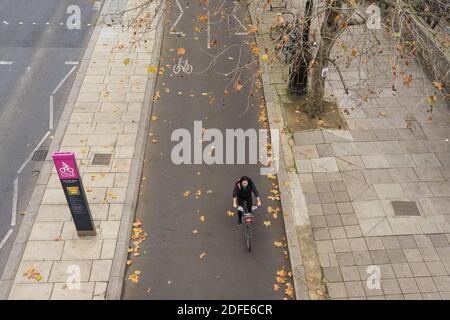 Victoria Embankment pista ciclabile segregata vista dall'alto con un ciclista in movimento che attraversa le foglie cadute sulla strada. Londra Foto Stock