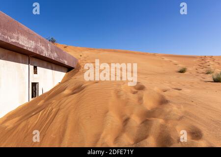 Vecchio edificio residenziale sepolto in duna di sabbia su un deserto nel villaggio fantasma di al Madam a Sharjah, Emirati Arabi Uniti. Foto Stock