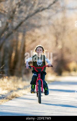 Felice ragazzo che cavalca la sua bicicletta su un sentiero lastricato; Salida; Colorado; USA Foto Stock