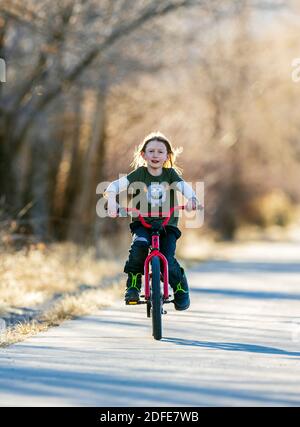 Felice ragazzo che cavalca la sua bicicletta su un sentiero lastricato; Salida; Colorado; USA Foto Stock