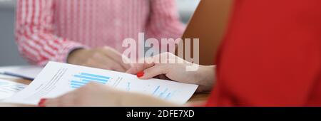 Due donne d'affari al tavolo di lavoro discutono di grafici con indicatori commerciali Foto Stock