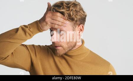 Ritratto di giovane uomo stanco che controlla la temperatura sensazione di malessere isolato su sfondo bianco Foto Stock