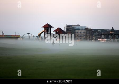 Ayr Low Green Pavilion , Ayrshire, Scozia, Regno Unito. Un marinaio o un lear avvolge il centro ricreativo Pavilion in una nebbia di basso livello. È un fenomeno insolito per la costa occidentale della Scozia. Dalla nebbia emerge un fiqure solitario Foto Stock