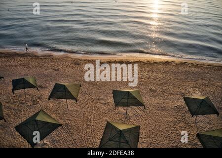 Ombrelloni da spiaggia all'alba. La corrente del mare nuota contro le onde sul mare bello Foto Stock