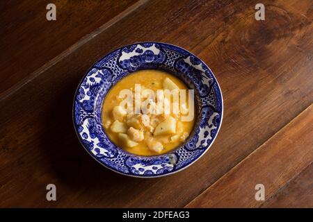 Antico piatto decorato con stufato di merluzzo e patate su rustico legno di castagno sfondo. Ricette di cucina con pesce e verdure. Foto Stock